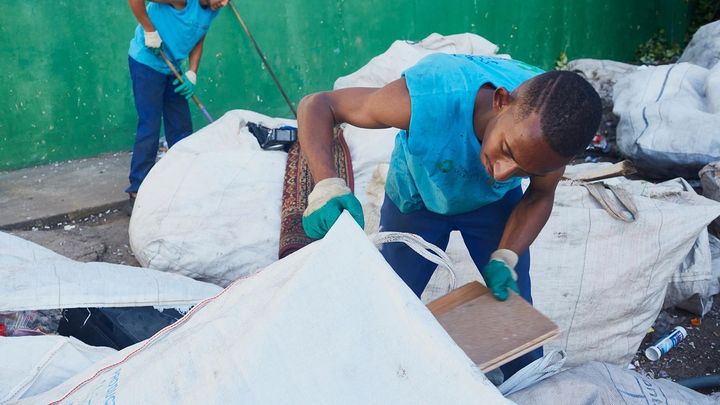 Two men sort through sacks of waste in a recycling centre in Brazil