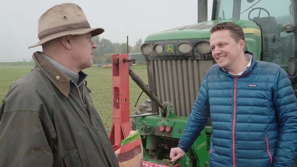 Two farmers stood by a tractor in a field