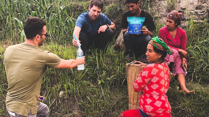 A group of people holding a bottle of water and using water purifier