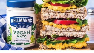 Jar of Hellmann’s vegan mayo on a chopping board. Next to it is a seeded sandwich with salad filing