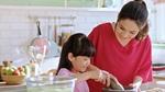 A mother and daughter cook together in a kitchen