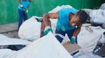 Two men sort through sacks of waste in a recycling centre in Brazil