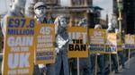 line of people dressed as silver living statues on a bridge in london carrying various signs.