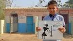 A boy holding a drawing of a person with a broom and Gandhi glasses on the side with the text- Ek kadam swachhata ki or.