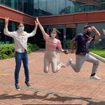 A group of people wearing masks jumping in the air in front of a Unilever office