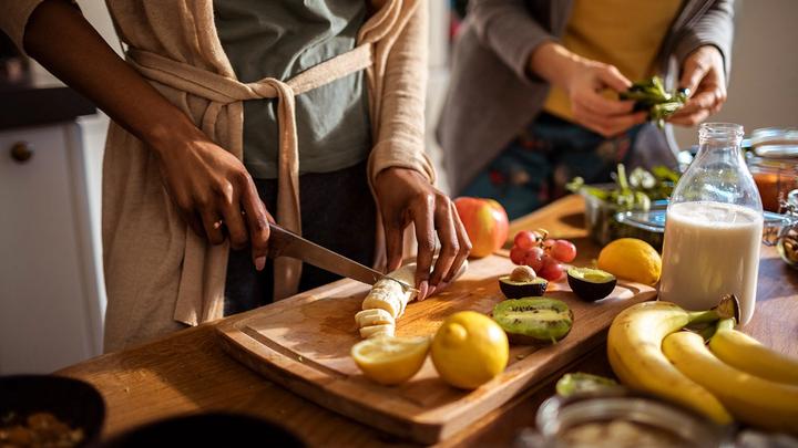 Close up shot of two pairs of hands preparing fruit and vegetables