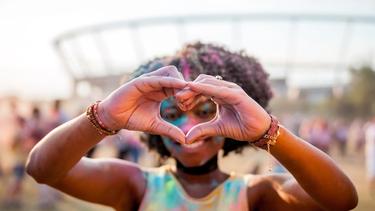 African American girl at a festival making a heart symbol with her hands