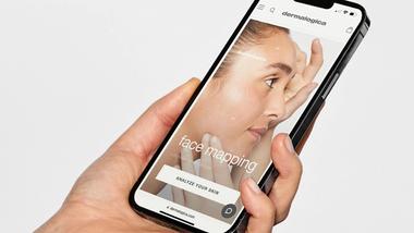 Hand holding mobile phone showing screenshot of Dermalogica’s face mapping app.