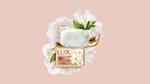 A pack of LUX Velvet soap surrounded by white jasmine flowers on a peach coloured background.