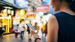 A girl looking at her mobile phone in a busy street in China.