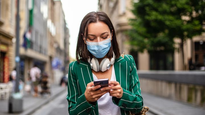 Woman walking in the city and checking her smartphone