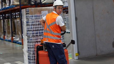 Worker in overalls and hard hat pulling a trolley across a factory floor