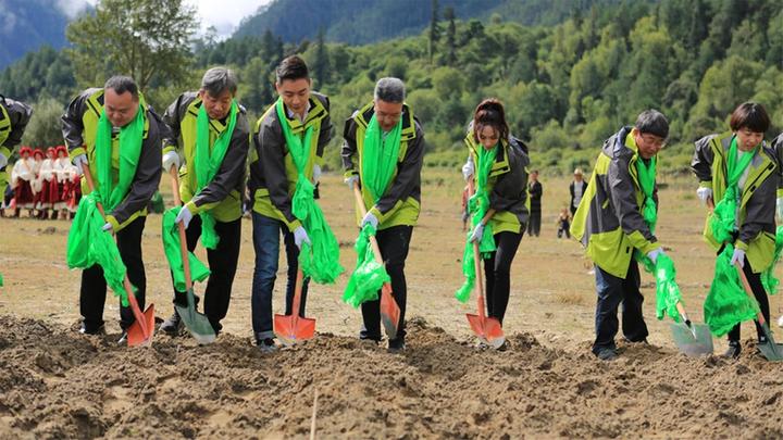 Photo of seven farmers in high vis jackets digging in field