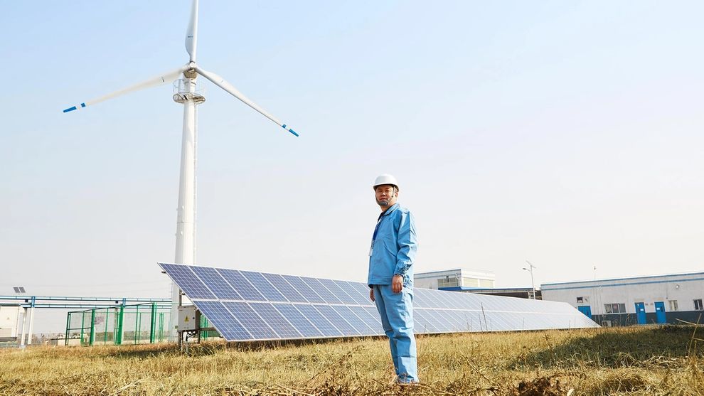 Man standing in front of solar panels and wind turbines at Unilever China factory
