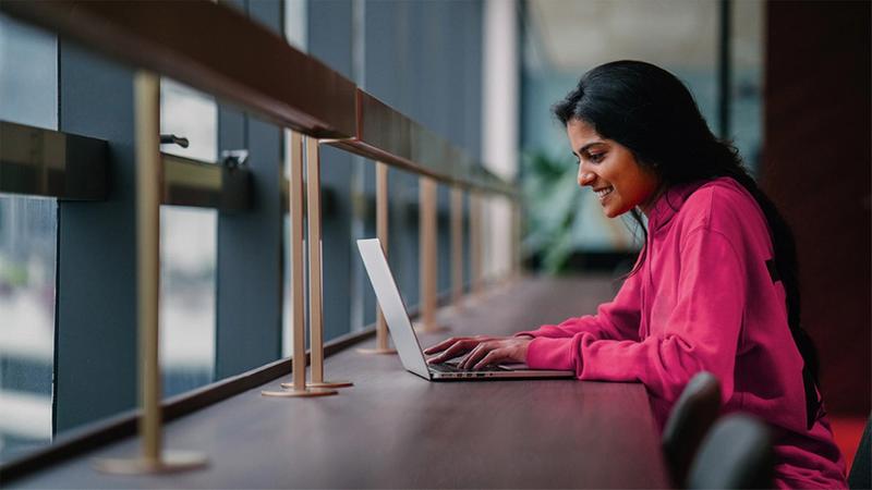 Woman in pink shirt working on a laptop