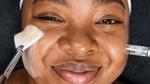 Young woman with melanin-rich skin undergoing a beauty treatment from a Dermalogica skincare professional 