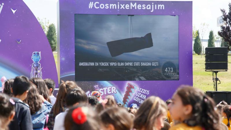 A crowd of people watching a screen showing Twister Cosmix ice lolly being launched into space