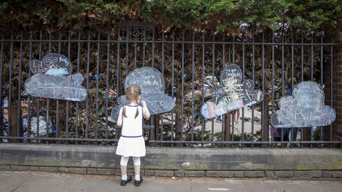 Young girl writing on a paper cloud hanging on a fence
