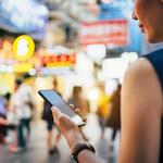 A girl looking at her mobile phone in a busy street in China.