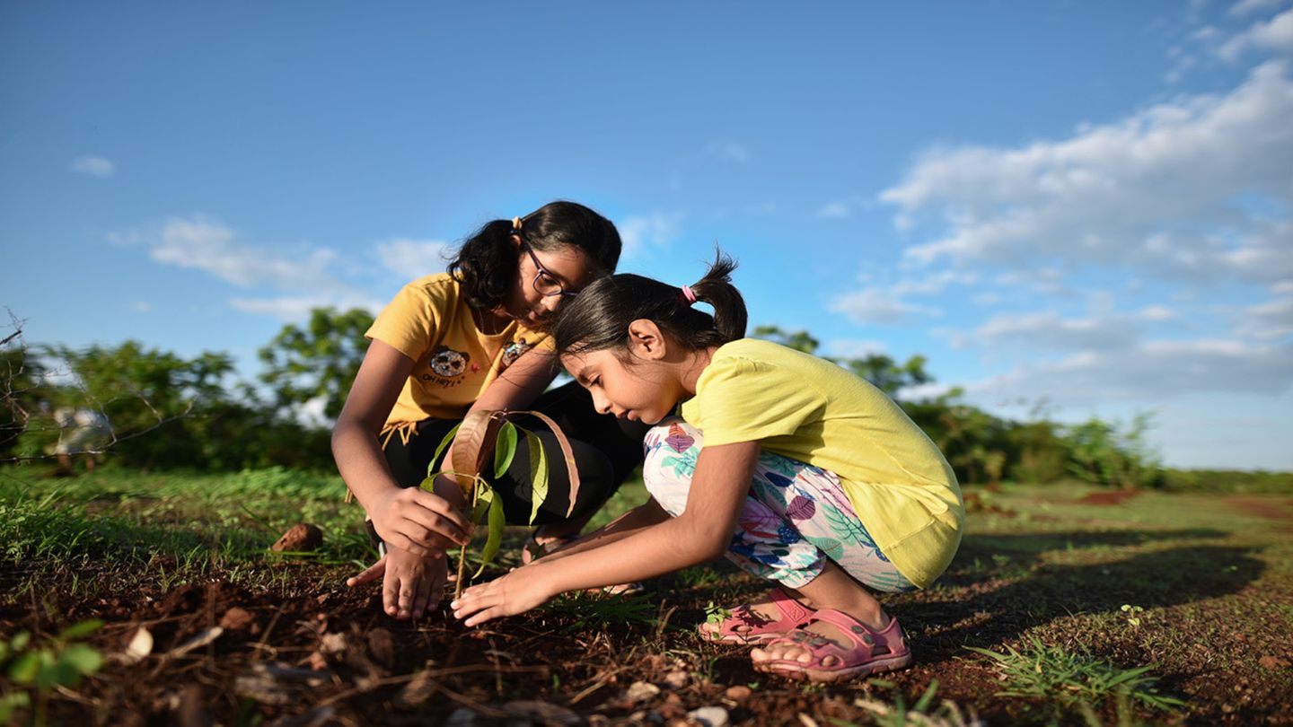 Two girls planting a plant