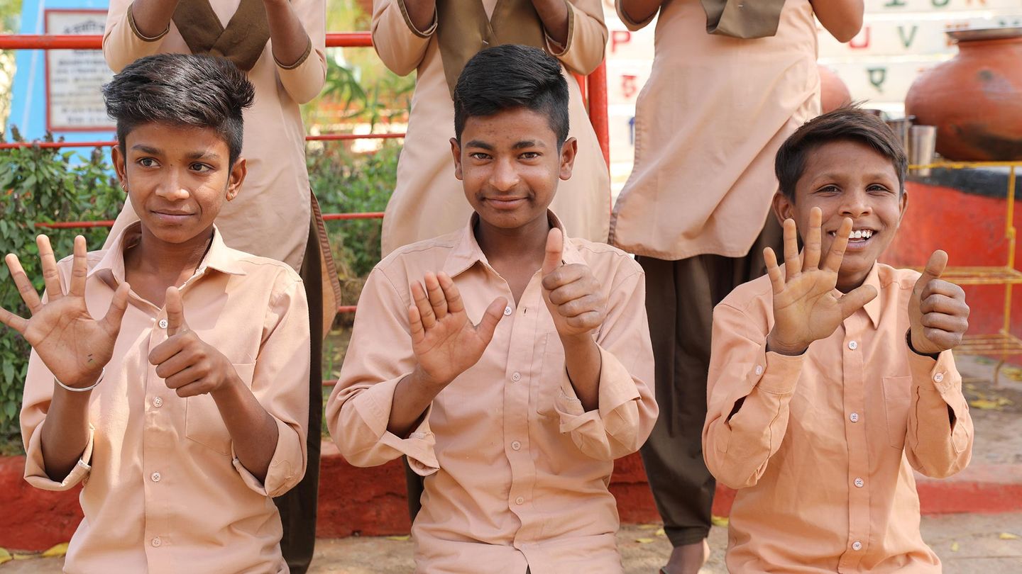 Three boys waving at the camera