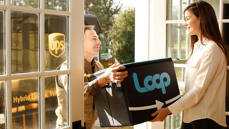 A delivery driver handing a lady a Loop parcel