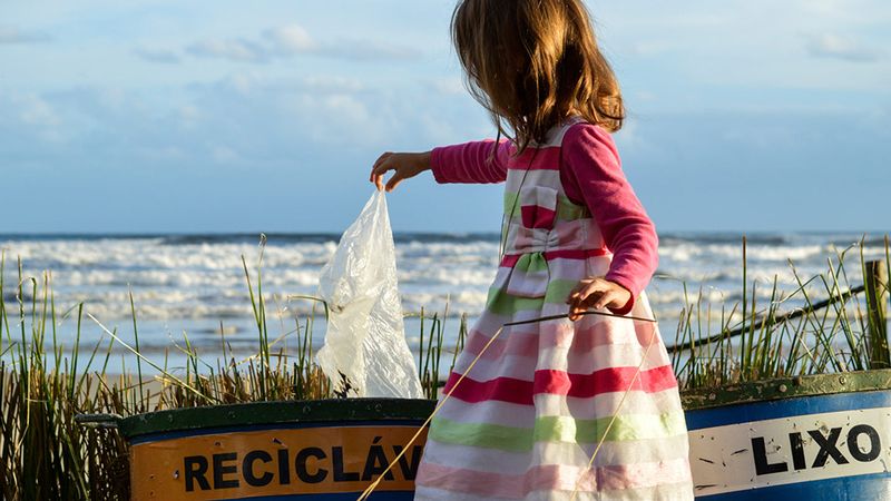 A young girl recycling a plastic bag