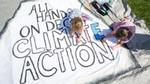 Two girls colouring in an 'All hands on deck climate action' poster