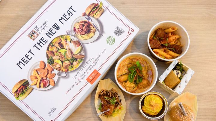 A box of The Vegetarian Butcher's NoChicken products laid out beside six dishes made with the plant-based protein