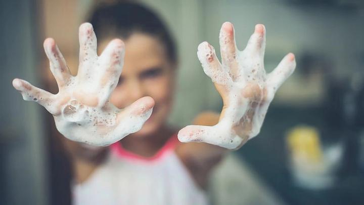 Boy with soapy hands showing at camera