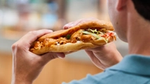 Back view of a man preparing to eat a large döner kebab