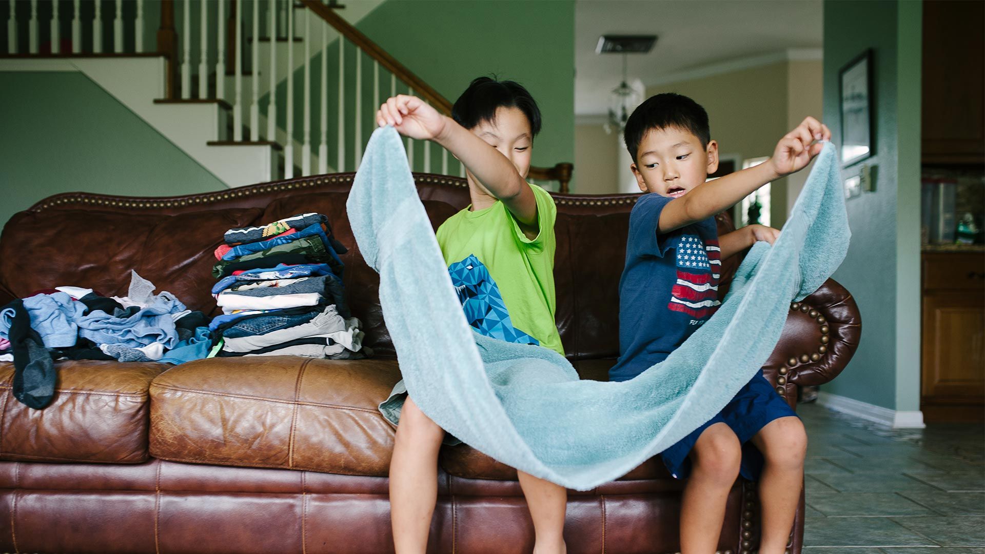 Two boys folding a towel