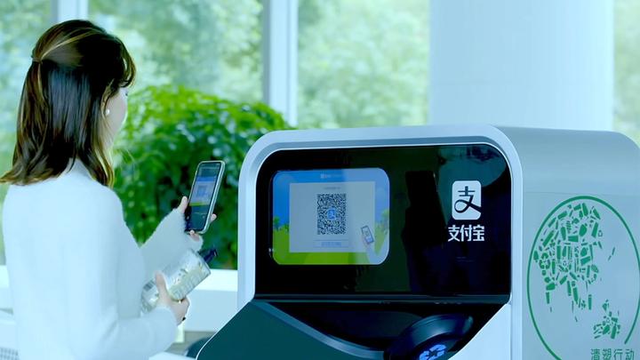 Woman holding plastic bottle ready to scan its QR code into an AI-enabled recycling and sorting machine