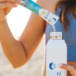 Woman pouring powdered Liquid I.V. electrolyte drink mix from a sachet into a bottle.