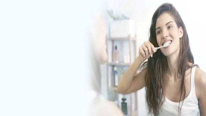 Woman brushing her teeth with an electric toothbrush