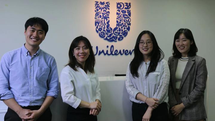 Unilever employees posing in front of Unilever logo