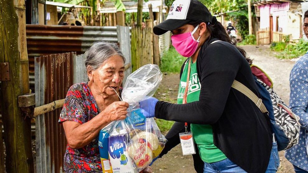 Yonger woman handing over a food package to an older woman