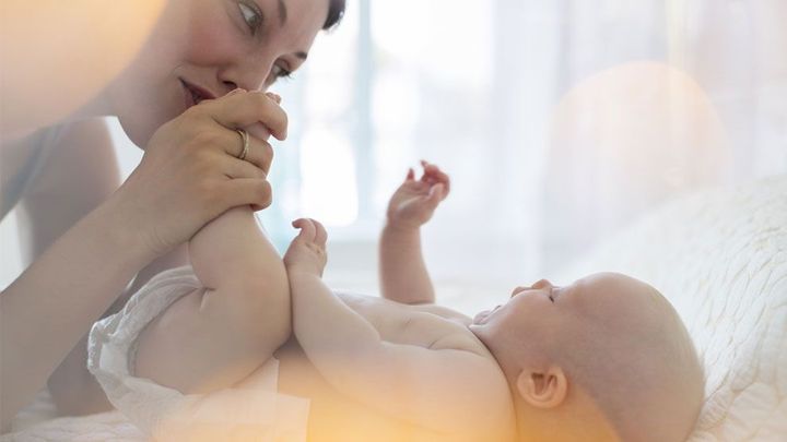 Жена целува бебе по крачетата