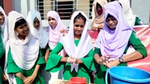 Schoolchildren in green uniforms with white hijabs washing their hands at a public tap