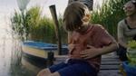 Young boy by a lake looking at dirty t-shirt 