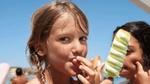 Ένα μικρό κορίτσι γλύφει τα δάχτυλά της και τρώει ένα παγωτό ξυλάκι