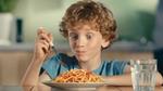 A boy eating a plate of spaghetti