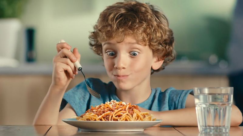 A boy eating a plate of spaghetti