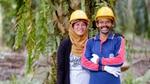Two smiling smallholder farmers standing beside their oil palms