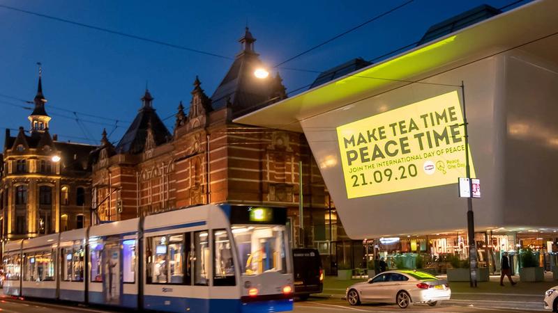 Photo of Make Tea Time Peace Time logo illuminated on front of building