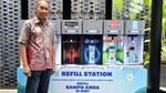 Man standing in front of Unilever’s in-store refill station in Indonesia. Machine has dispensers for products including TRESemmé, Clear and Lifebuoy.