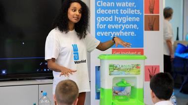 Woman explaining WaterAid’s work to school children