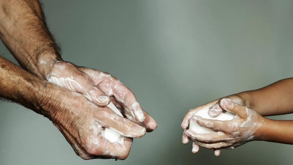 Photo of two sets of soapy hands washing with soap 