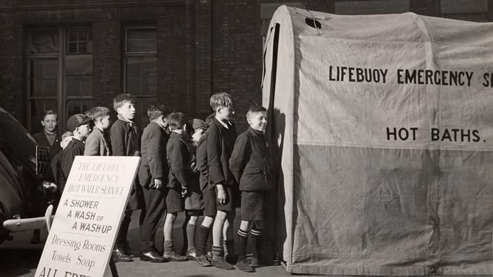 A photograph of young boys queuing for Lifebuoy's public aid emergency washing service during the Blitz in World War 2.