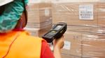 A factory worker scans a stack of cardboard boxes